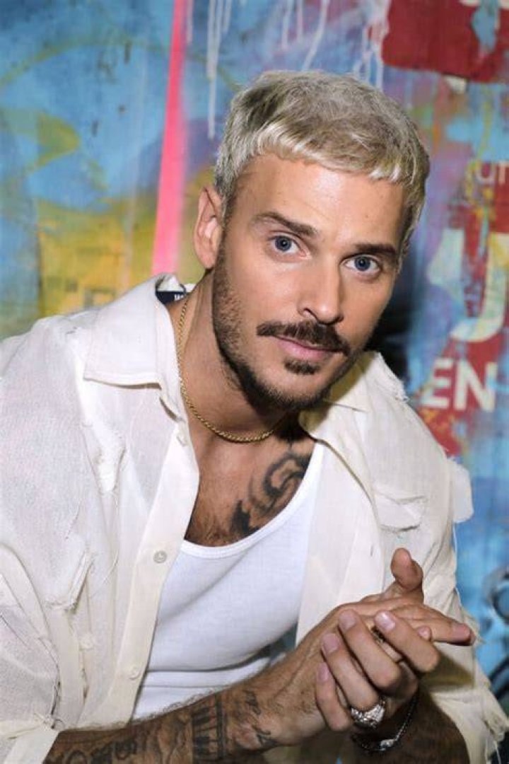 M. Pokora in a white shirt with his wife in a black dress.